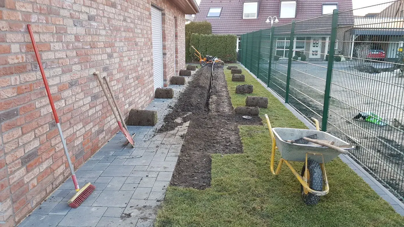 Mit dem Sodenschneider aufgenommene Rasensoden neben einem offenen Rohrgraben