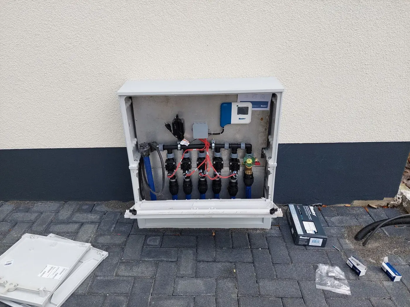 Geöffneter Ventilschrank mit Magnetventilen und Filter an einer Hauswand